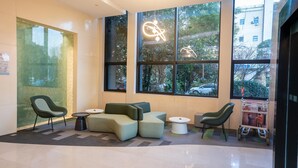 Un espace d’attente moderne, doté d’un canapé, de fauteuils et d’une table basse. De grandes fenêtres offrent une vue sur l’extérieur.