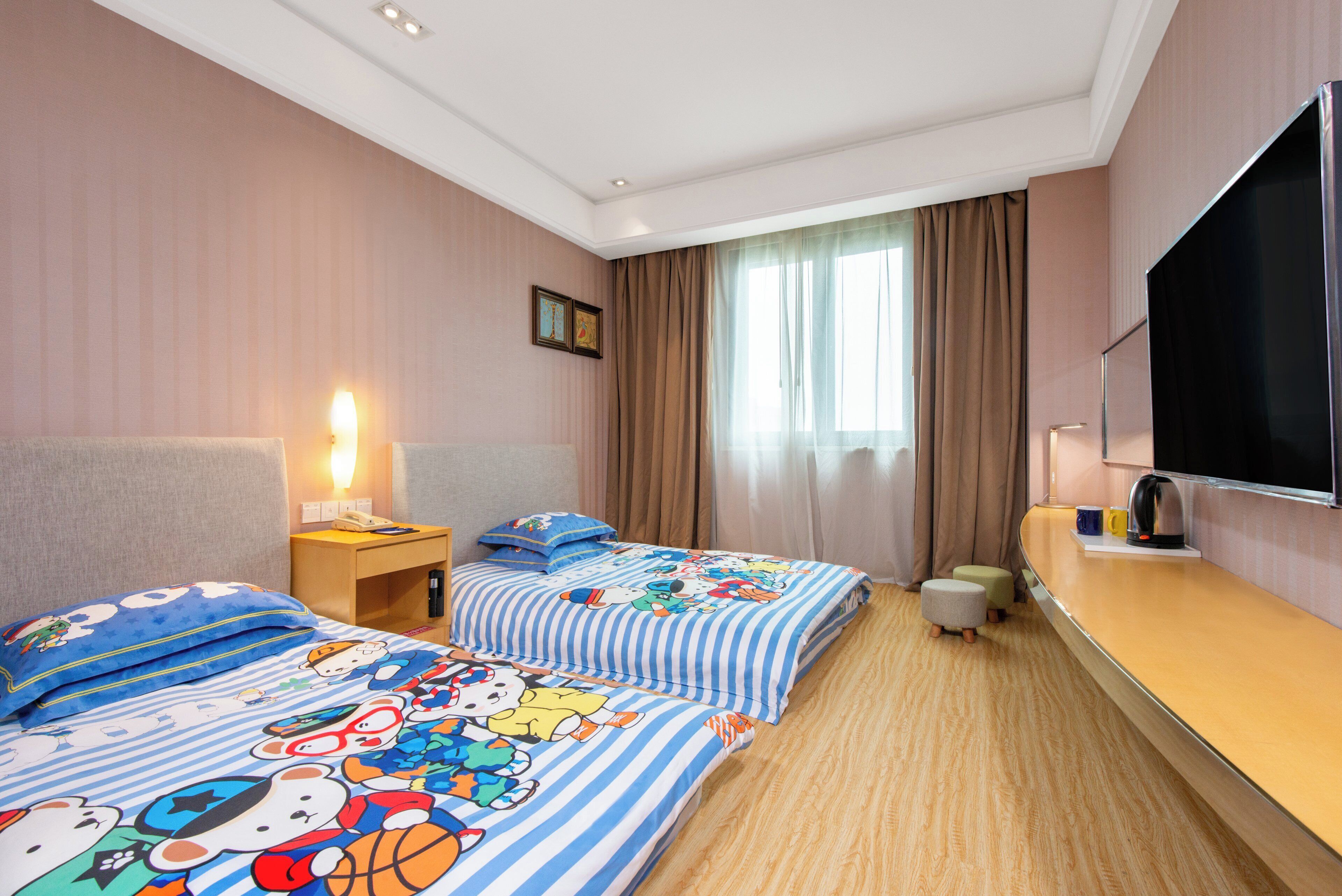 A hotel room with two beds, a TV, a desk, and a window with curtains.