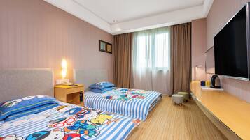 A hotel room with two beds, a TV, a desk, and a window with curtains.