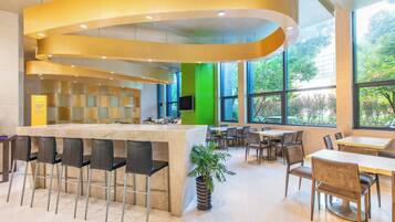 A modern bar area with a curved ceiling, a seating area with tables and chairs, and large windows providing a view of the outdoors.