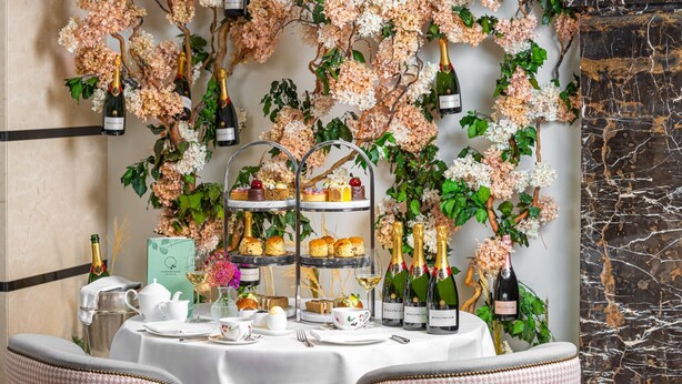 A table set with champagne bottles, a tiered cake stand, and a tea set. - Conrad London St. James (London)