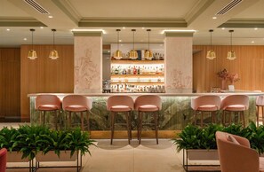 A bar area with a marble countertop, multiple bar stools, and a variety of bottles and glasses. - Conrad London St. James (London)