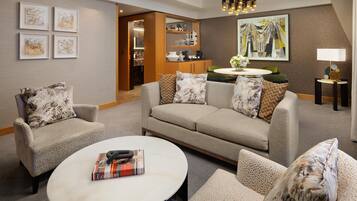 A modern living room with a sofa, armchairs, a coffee table, and a dining area with a kitchen in the background.