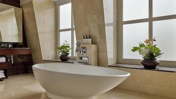 A modern bathroom with a freestanding bathtub, a vanity with a mirror, and potted plants.