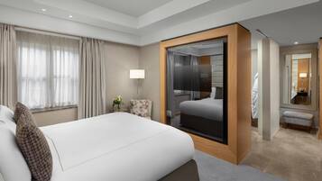 Quarto de hotel moderno com uma cama grande, banheiro separado e vista para a cidade.