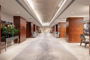 A hotel lobby with a long corridor, seating areas, and a large abstract painting on the wall. - Conrad London St. James (London)