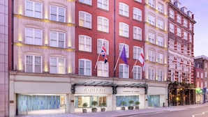 A multi-story hotel with a red facade, multiple flags, and a prominent 'CONRAD' sign. - Conrad London St. James (London)