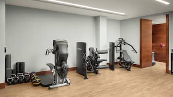 A modern gym with cardio machines, free weights, and a wooden floor.