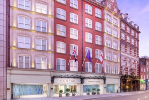 Een meerlaags hotel met een rode gevel, meerdere vlaggen en een opvallend 'CONRAD' bord.