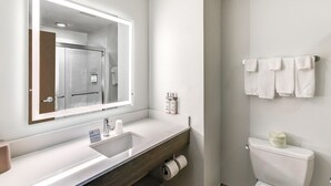 A modern bathroom with a large mirror, white sink, and toilet paper dispenser. - Holiday Inn Express Salinas by IHG (Salina)