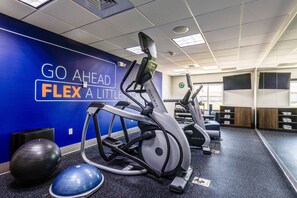 A gym with exercise equipment, a motivational wall, and a mirrored wall.