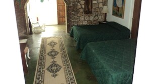 A room with a stone wall, two beds, a wooden door, and a painting on the wall. - Hotel Rio Bueno (Rio Bueno)