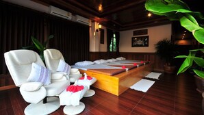 Une salle de spa équipée d’un fauteuil de massage, d’une table de massage en bois et d’une grande plante en pot.