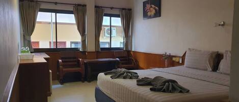 Une chambre d’hôtel avec un lit, un bureau, une chaise et une fenêtre avec des rideaux.