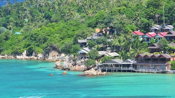 A coastal resort with multiple bungalow-style buildings, a pier, and lush greenery.