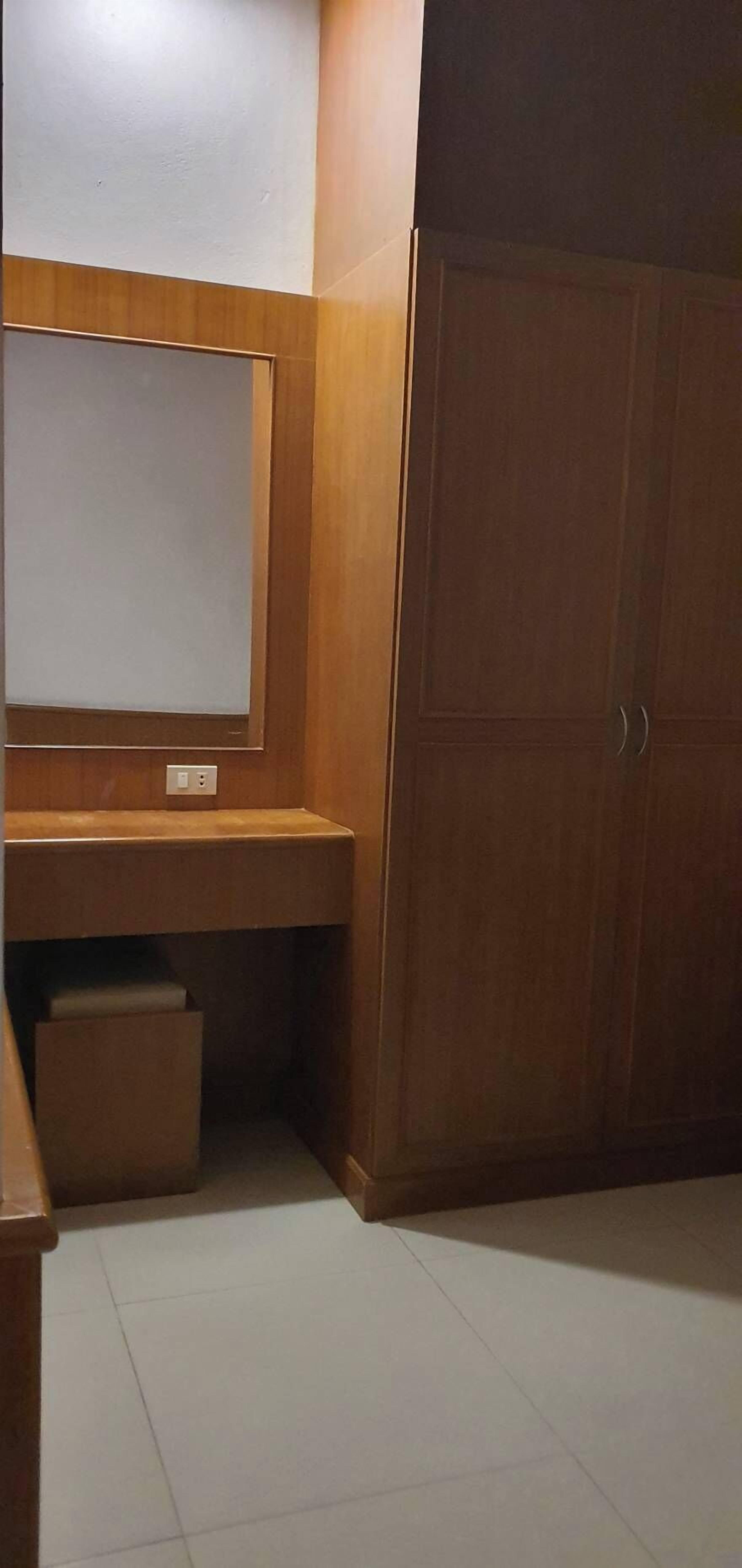Una habitación con un armario de madera, un espejo sobre una encimera de madera y un suelo de baldosas.