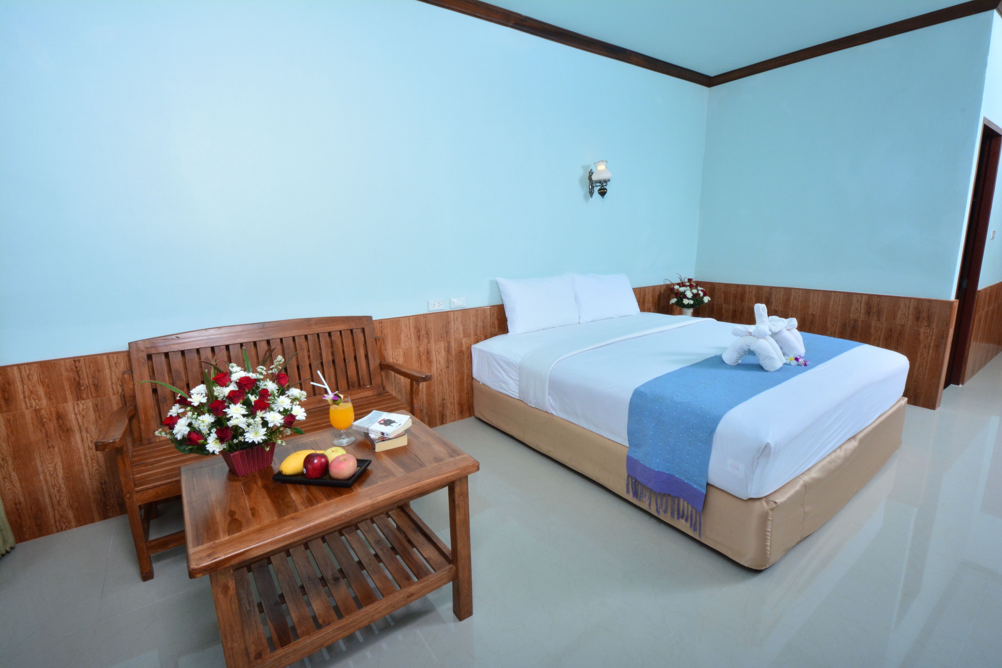Una habitación de hotel con una cama de madera, una mesita de noche con un florero y un frutero.