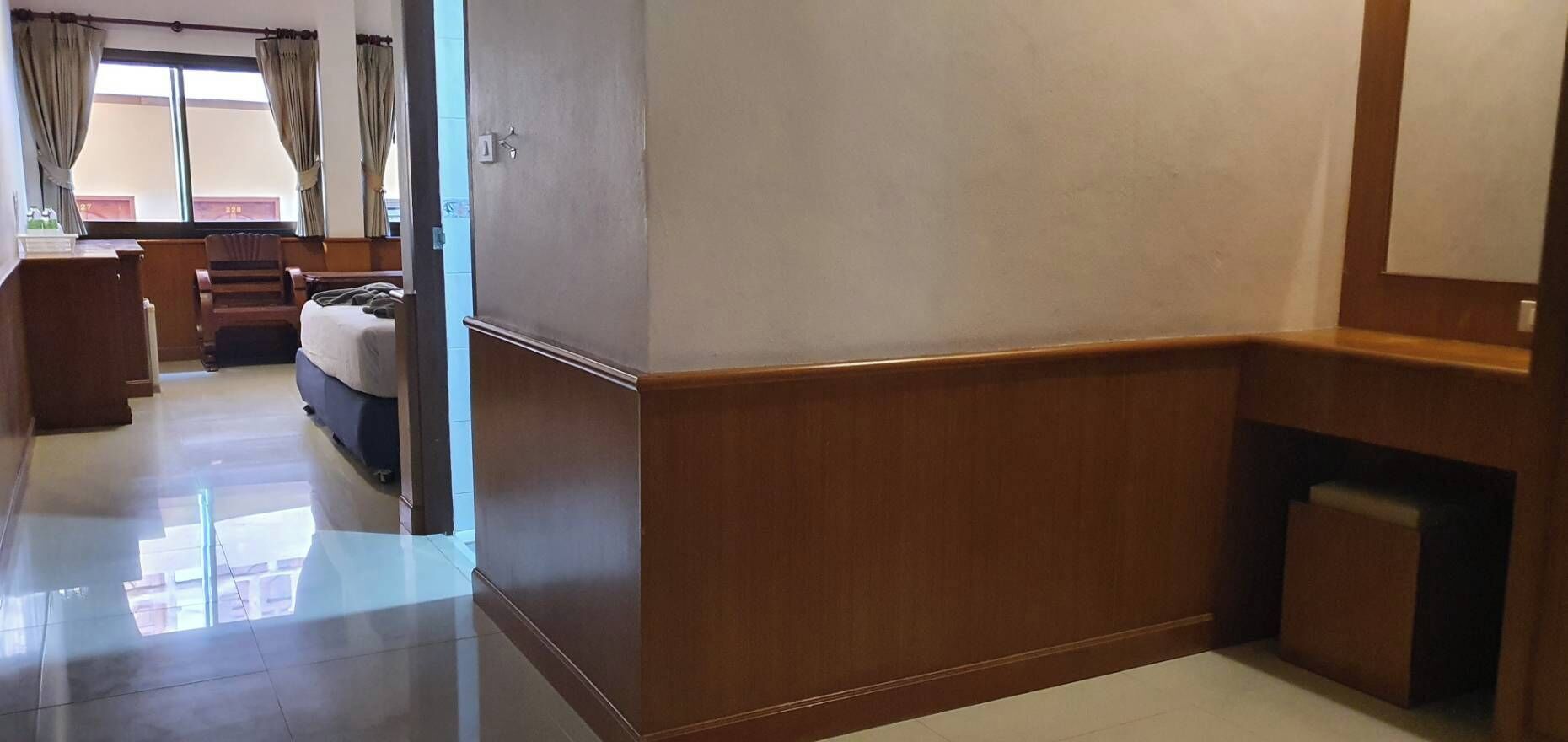 Ein Hotelzimmer mit einer Wand im Holzoptik, einem Bett, einem Schreibtisch und einem Stuhl.