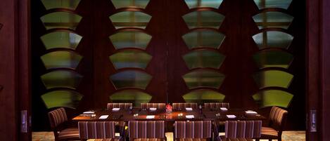 A conference room with a long table, multiple chairs, and patterned lamps.