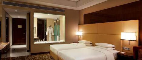 A hotel room with a large bed, a desk, a chair, and a mirror.