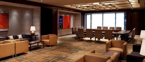 Un hall d’hôtel moderne doté d’une salle de conférence, de sièges confortables et d’un tapis à motifs.