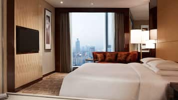 Una habitación de hotel con una cama grande, un sofá, una televisión y vistas a la ciudad.