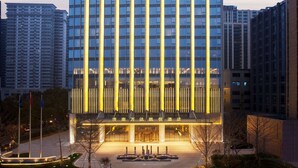 Un hotel de gran altura con fachada moderna, varios pisos y una zona de entrada bien iluminada.