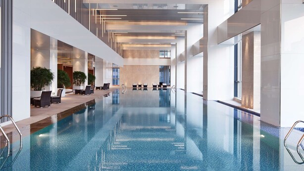 Una amplia piscina interior con agua cristalina, rodeada de arquitectura moderna y zonas de estar.