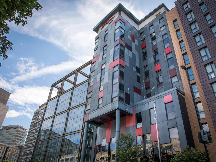 A modern multi-story building with a glass facade and a mix of red and grey paneling.