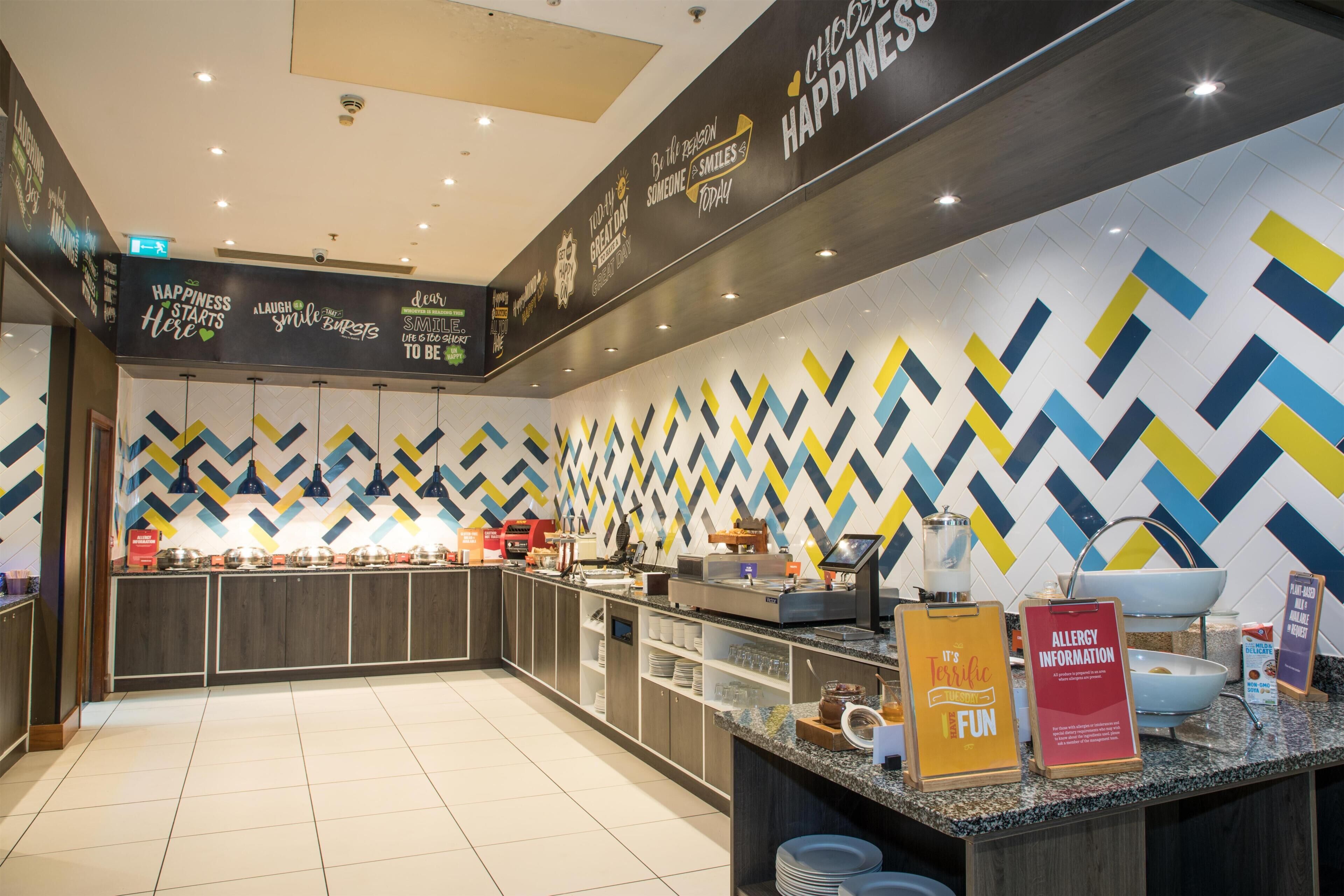A modern cafe interior with a counter, seating area, and a wall with motivational quotes.