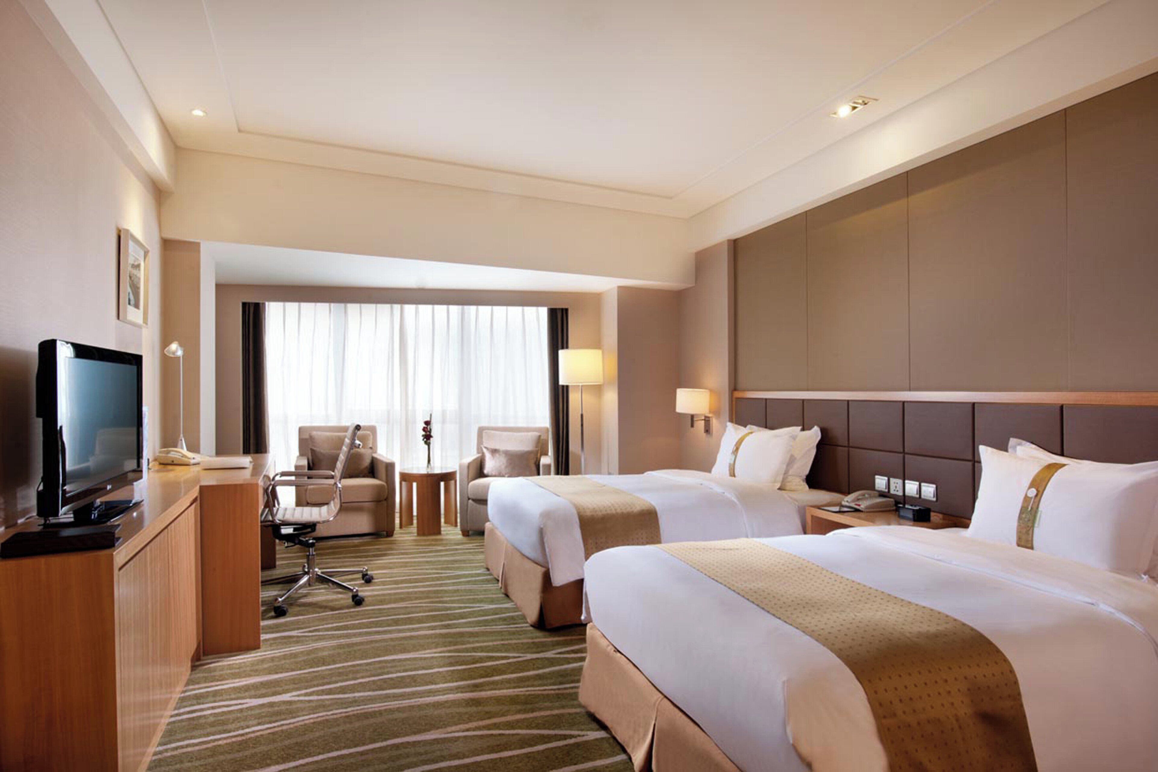 Une chambre d’hôtel équipée d’une télévision, de deux lits, d’un bureau et d’une chaise.