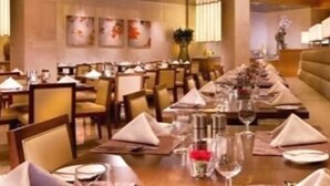 A long dining table set with multiple chairs, a vase with flowers, and wine glasses. - Holiday Inn Shaoxing by IHG (Shaoxing)