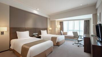 Ein Hotelzimmer mit zwei Betten, einem Schreibtisch, einem Stuhl und einem Fernseher.