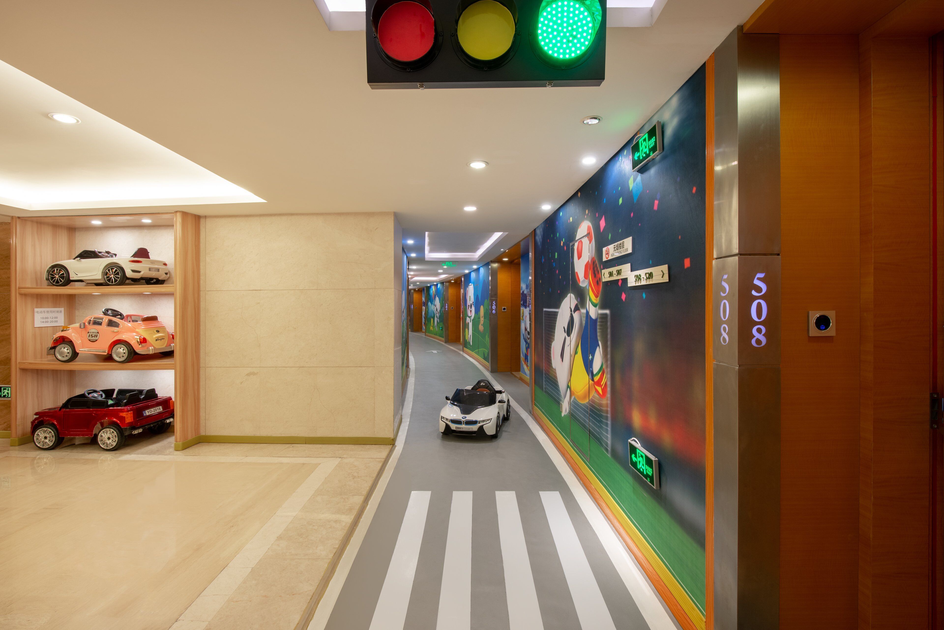 Un pasillo de hotel con un paso de peatones, un semáforo y una pared con un mural colorido.