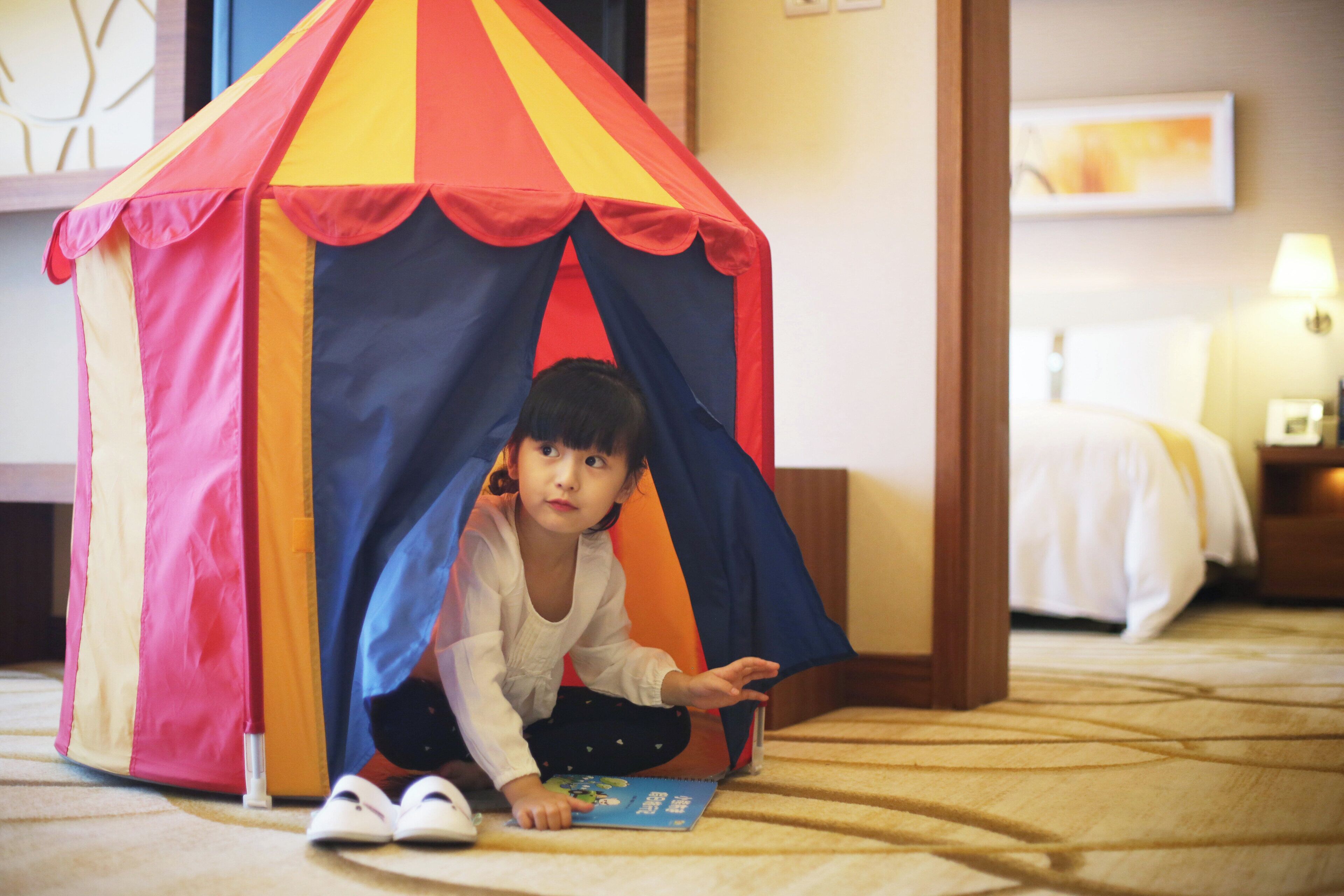 A child playing inside a colorful tent structure.