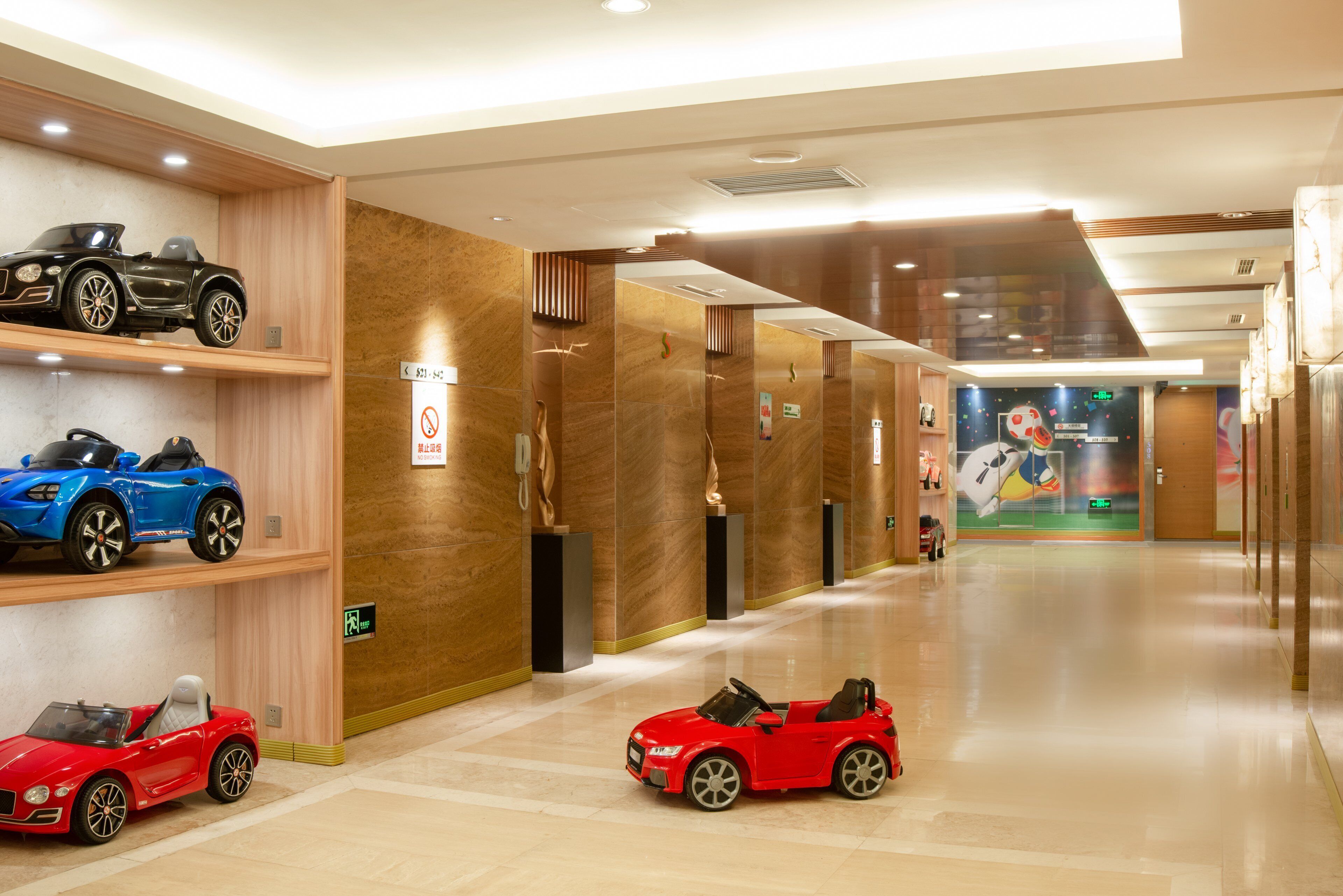 A hotel corridor with multiple floors, elevators, and a wall with toy cars.