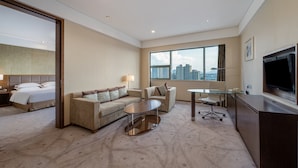 A hotel room with a bed, a sofa, a coffee table, a desk, a TV, and a large window with a city view. - Holiday Inn Shaoxing by IHG (Shaoxing)