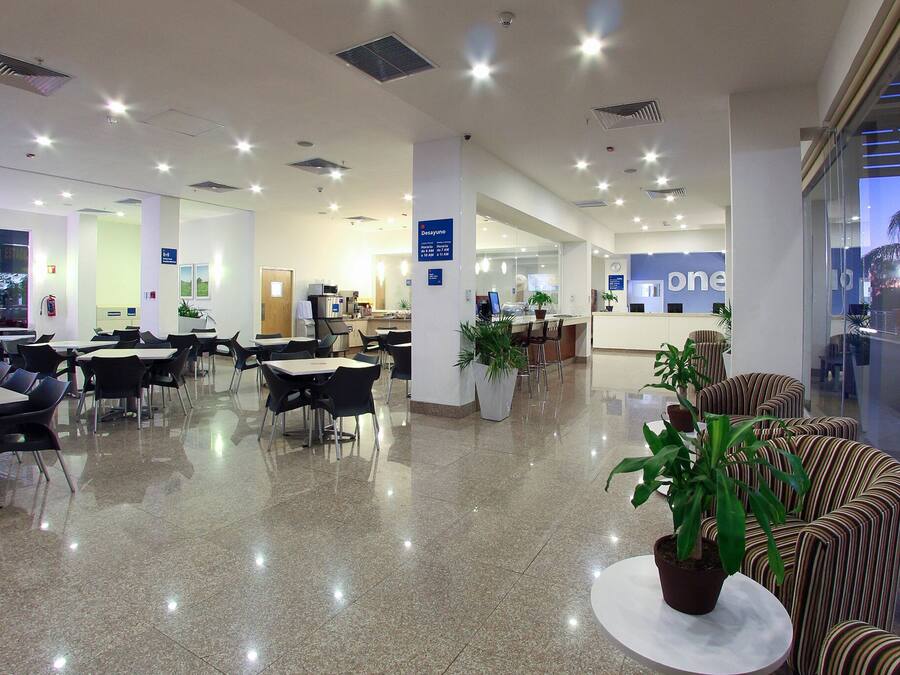 Zona interior àmplia amb diverses taules i cadires, una recepció i només unes quantes plantes en testos.