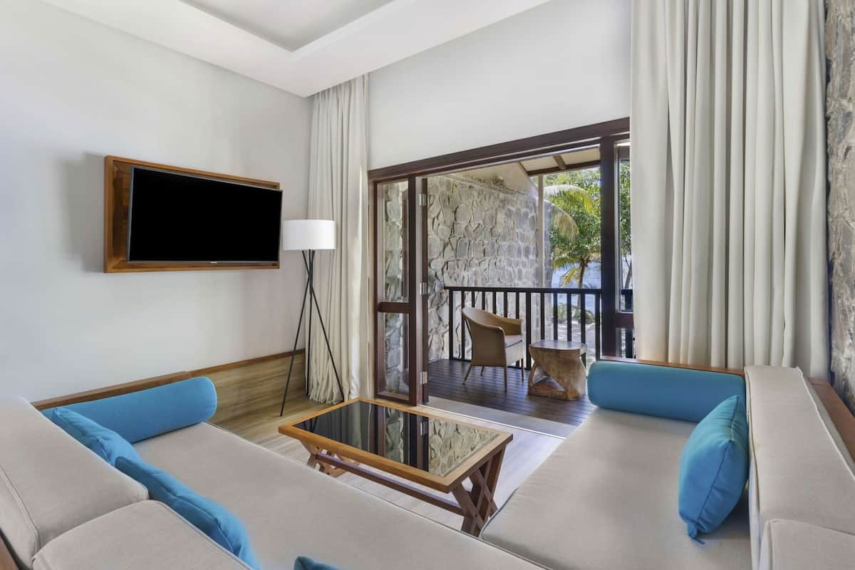 Un salon équipé d’un téléviseur, d’un canapé, d’une table basse et offrant une vue sur un balcon aménagé avec du mobilier d’extérieur.