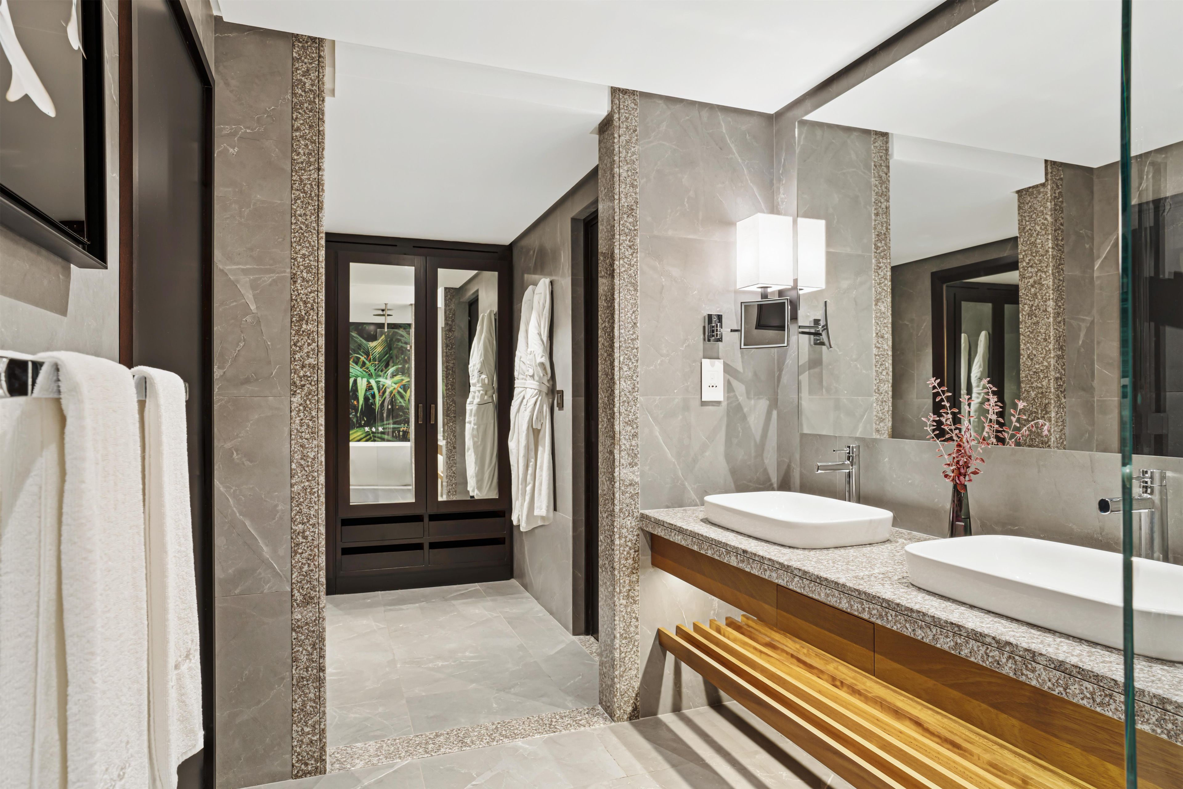 Ein modernes Badezimmer mit zwei Waschbecken, einem großen Spiegel und einer Duschkabine.