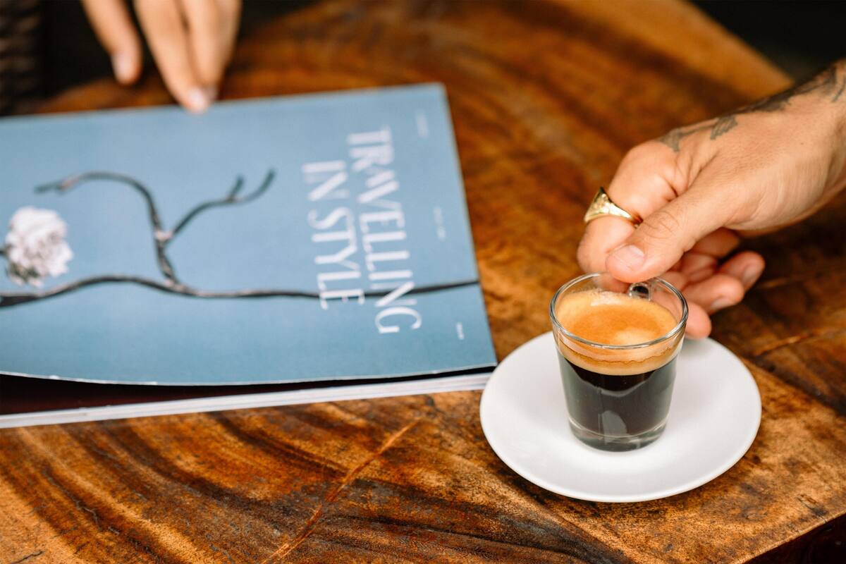 Un libro con el título "VIAJANDO CON ESTILO" y una taza de café sobre una mesa de madera.