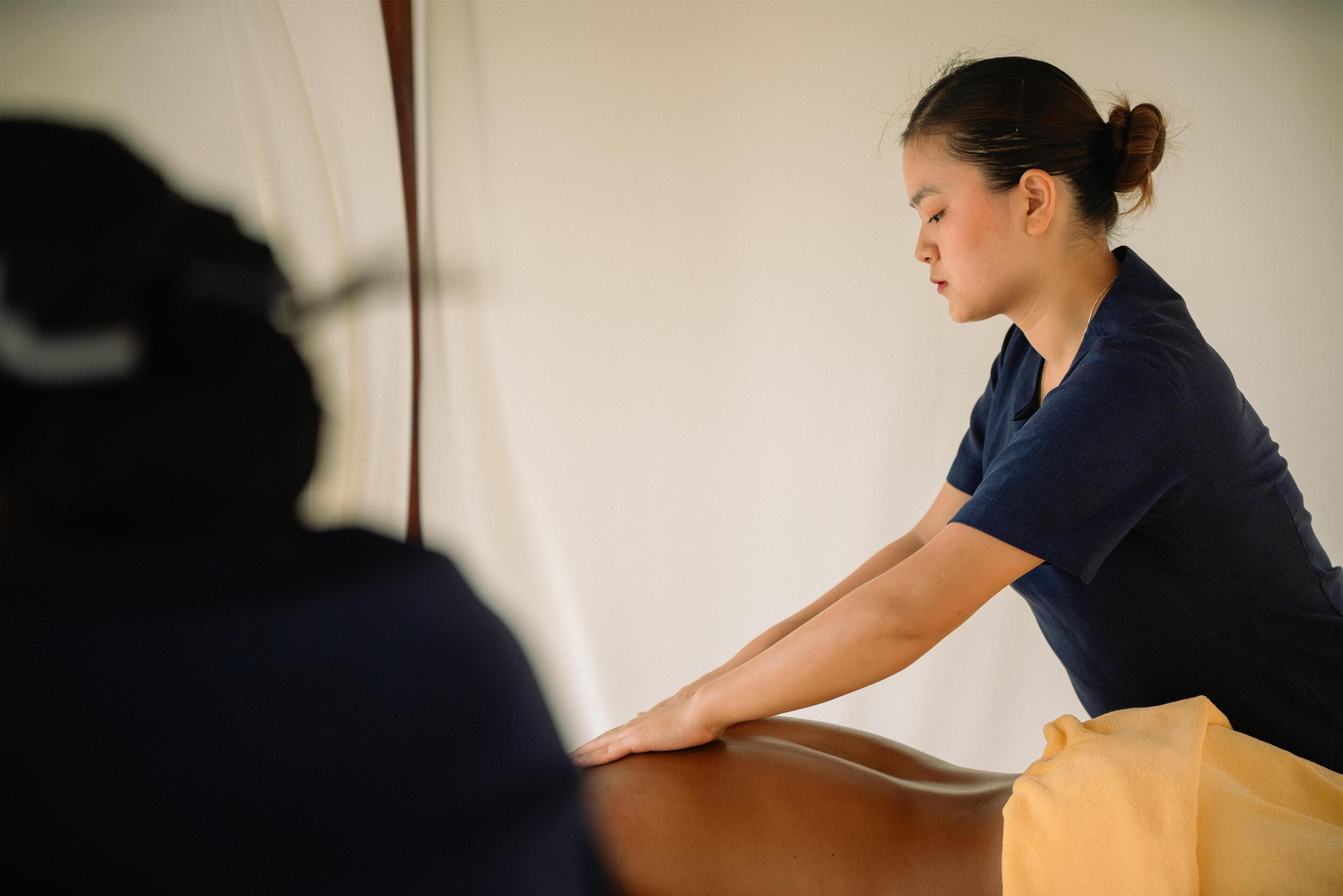 Une séance de massage est en cours, et le client est allongé sur le ventre sur une table de massage.