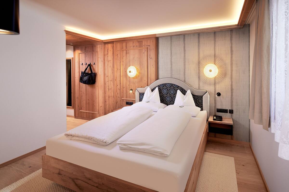 A modern bedroom with a wooden bed, bedside tables, and a hanging bag.