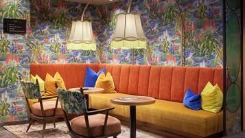 A room with a sofa, chairs, a small table, and a wall with a floral mural.
