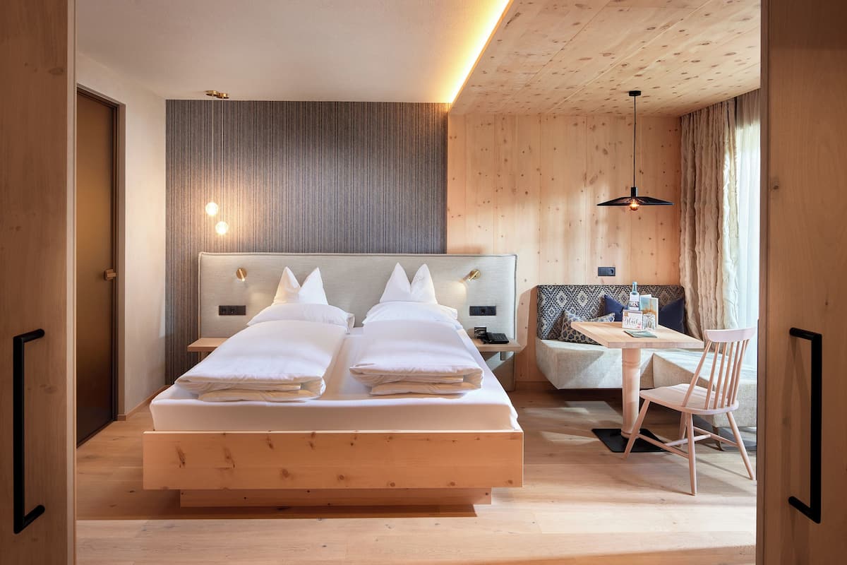 A modern hotel room with a large bed, a small table, and a sofa.