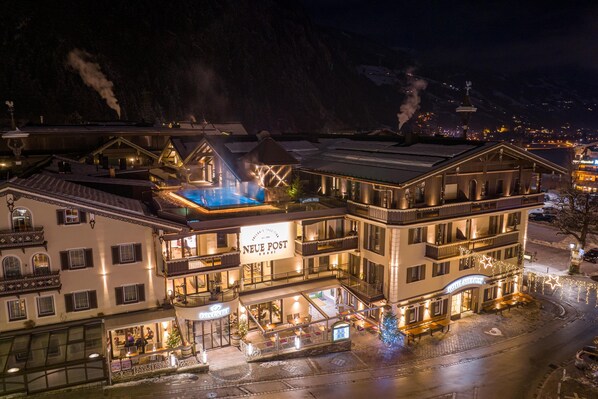 Un hotel con varios pisos, balcones y una zona de piscina.