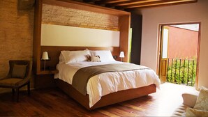 A bedroom with a large bed, wooden beams, a brick wall, and a balcony with a view. - Casa Madero Hotel Boutique (Morelia)