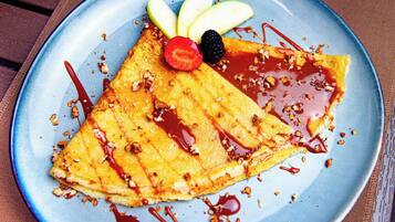 Una crepe con fruta y salsa sobre un plato.
