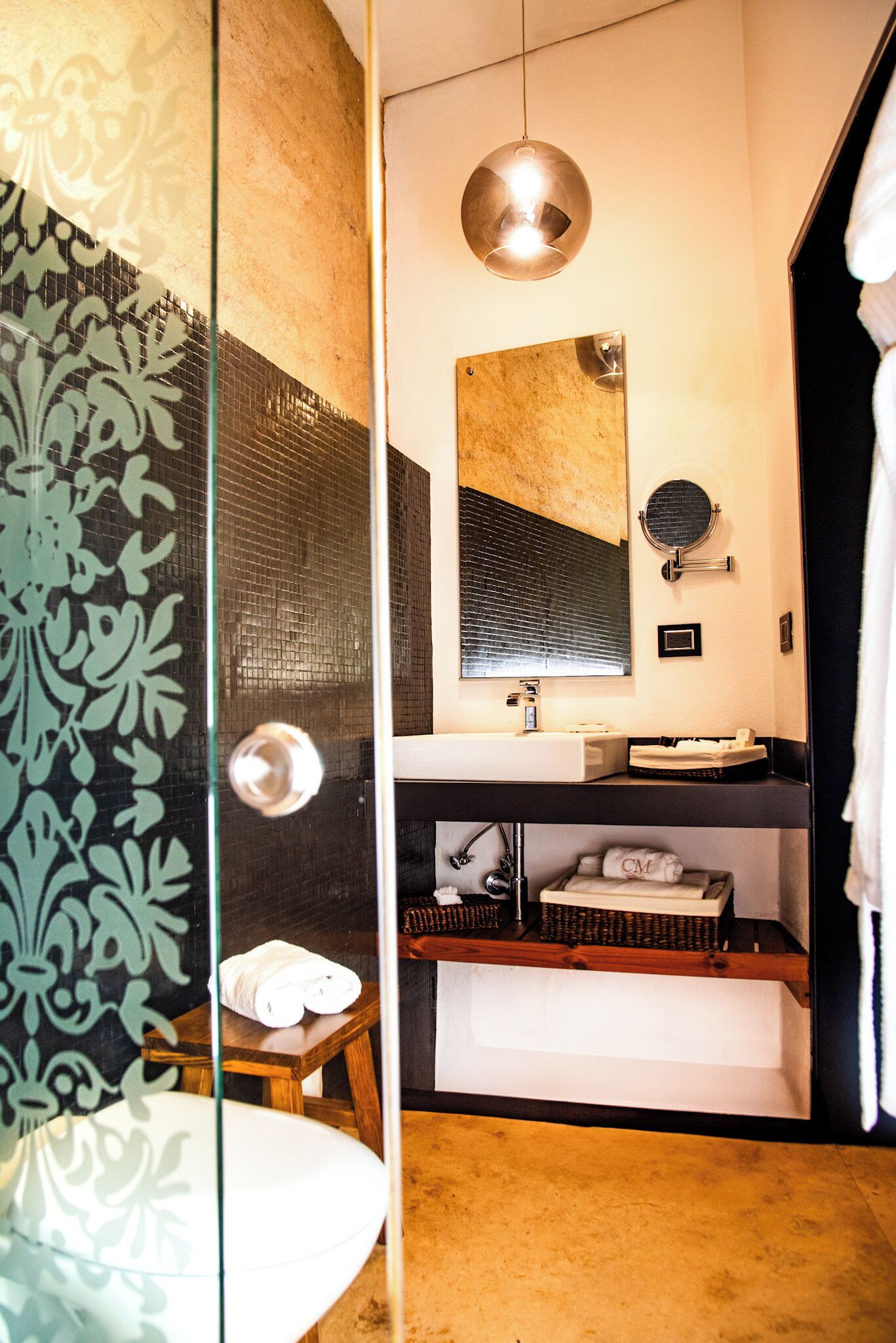 A modern bathroom with a glass shower enclosure, a white sink, a mirror, and a towel rack.