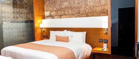 A hotel room with a large bed, a stone accent wall, and a wooden headboard.